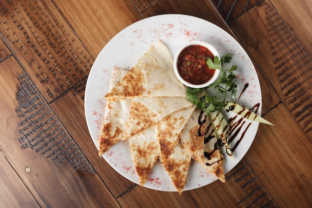 Quesadilla with beef and chicken on brown wood table. top view. quesadilla and sauce.