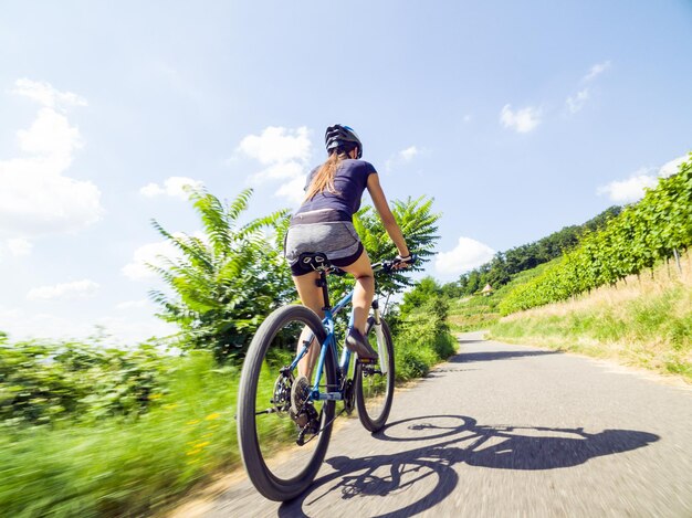 Photo rear view of woman riding bicycle on country road