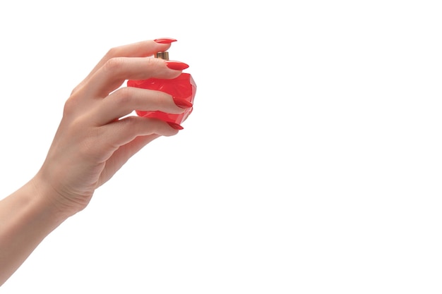 Red bottle of perfume in woman hand with red nails isolated on a white background