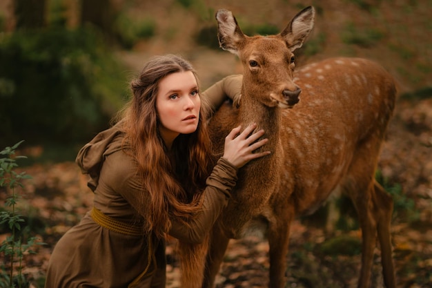 Redhead girl with deer in a long dress