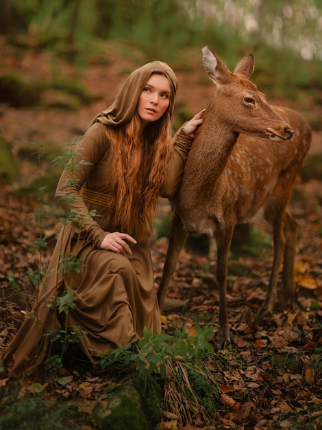 Redhead girl with deer in a long dress