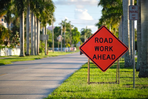 Road work ahead sign on street site as warning to cars about construction and utility works