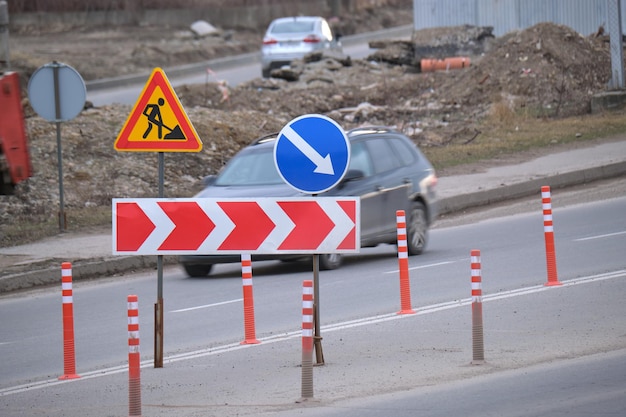 Roadworks warning traffic signs of construction work on city street and slowly moving cars