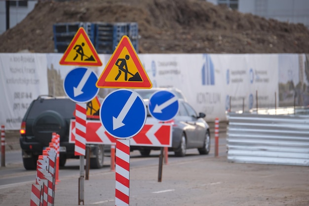 Roadworks warning traffic signs of construction work on city street and slowly moving cars