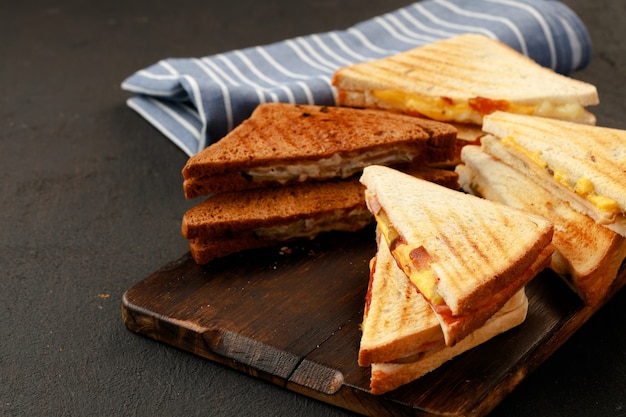 Sandwiches cut into halves on wooden cutting board with napkin on table