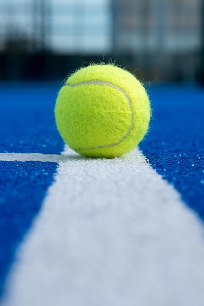 Photo selective focus of a ball on the white line of a blue paddle tennis court