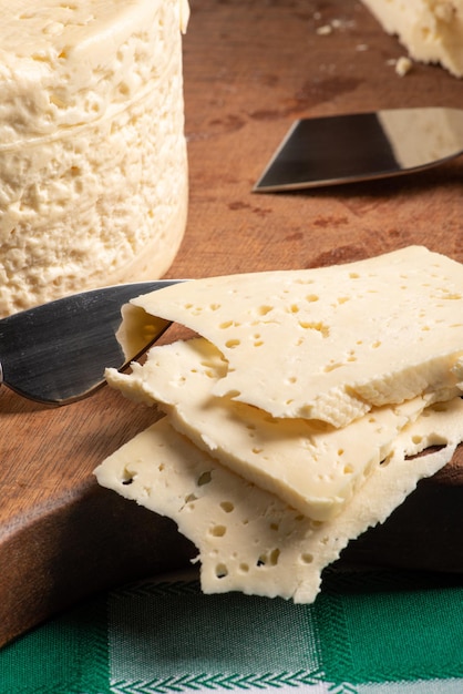 Semi-cured cheese from Brazil arranged on a rustic board on a green and white checkered tablecloth, selective focus.