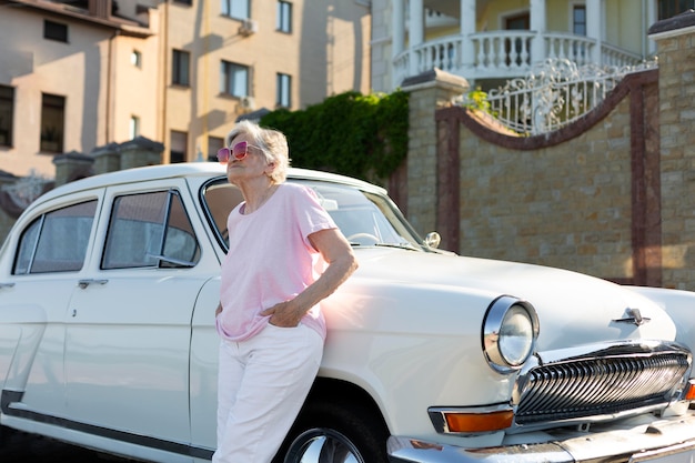 Senior traveler standing nest to her car