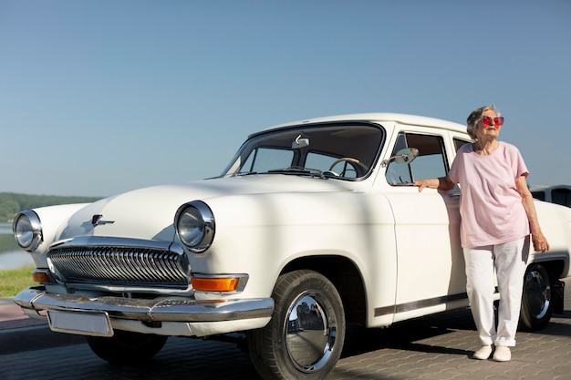 Senior traveler standing nest to her car