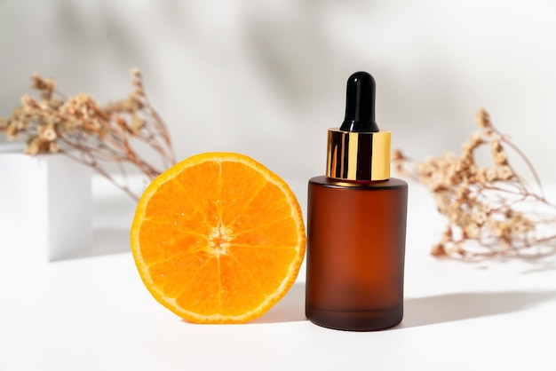 Serum bottle with dropper and slice of orange ingredients for skin care and treatment vitamin on white background Natural cosmetics concept