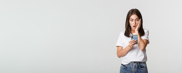 Shocked and impressed brunette girl looking amazed at smartphone screen