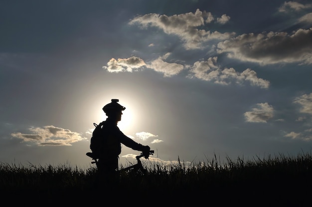 Silhouette of a cyclist with a bike in the sun