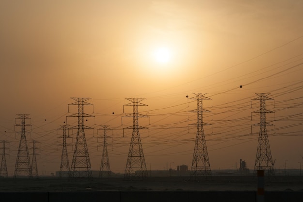 Photo silhouette electricity pylon by sea against sky during sunset