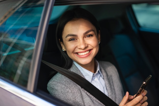 Smiley businesswoman with smartphone in the car