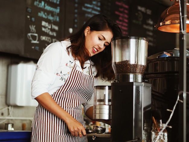 Photo smiling barista making coffee at cafe