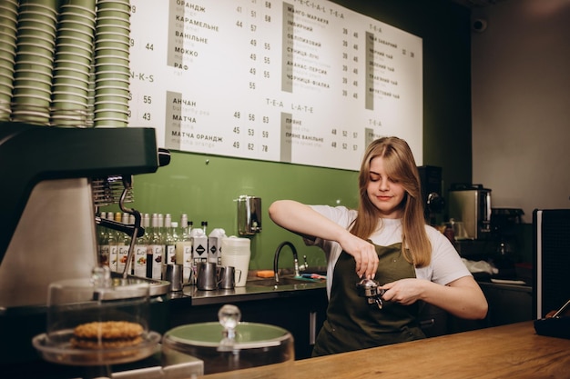 Photo smiling barista woman standing with coffee holder full of ground coffee in her hands barist work routine