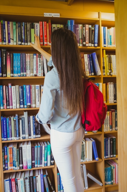 図書館で本を選ぶブルネットの学生の笑顔