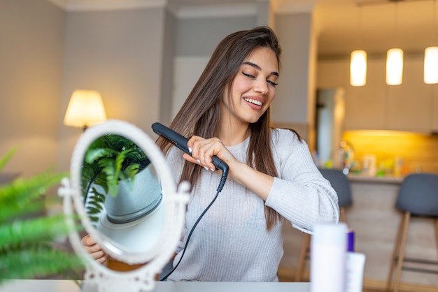 Smiling woman straightening hair in front of mirror.