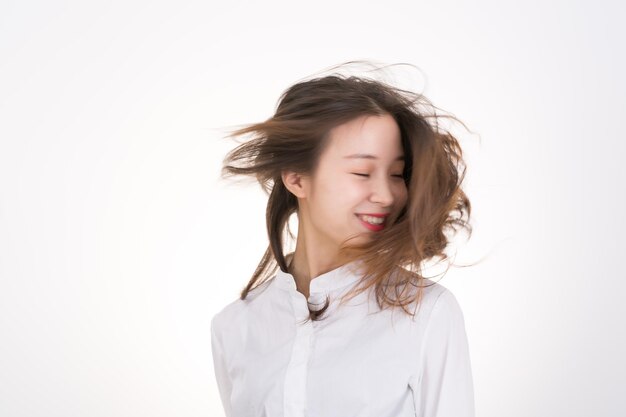 Photo smiling young woman tossing hair against white background