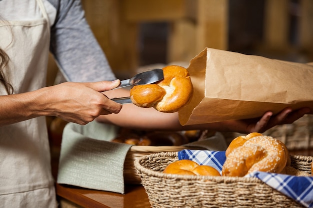 Photo staff packing bread in paper bag at bakery shop