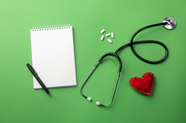 Stethoscope in doctors desk with notebook and heart