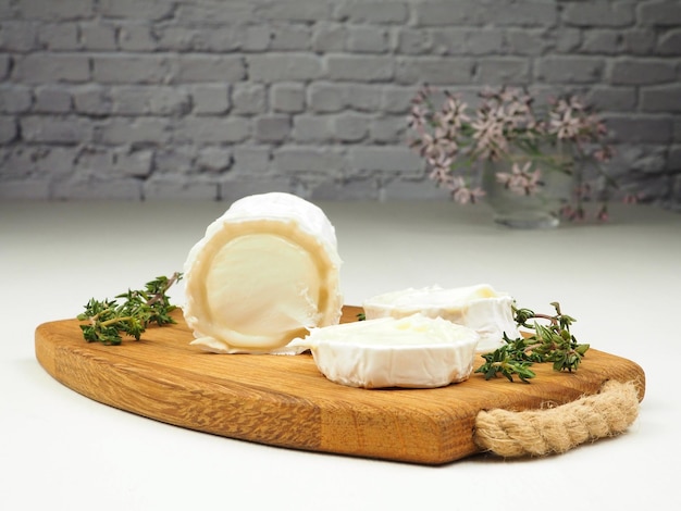 Photo stick of goat soft cheese and thyme sprigs on a white background