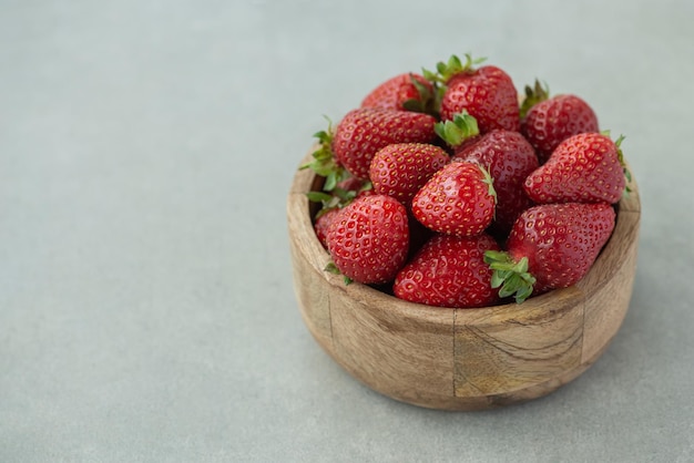 Strawberries in a wooden plate on a gray background