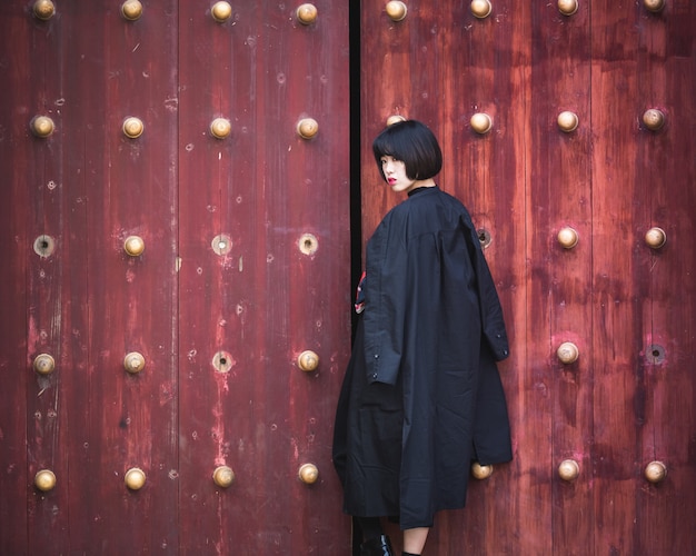 stylish woman standing front of traditional wooden door