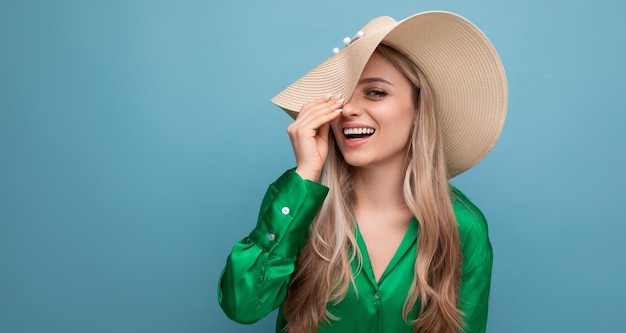 Stylish young woman tourist on vacation in a summer straw hat on a blue studio background