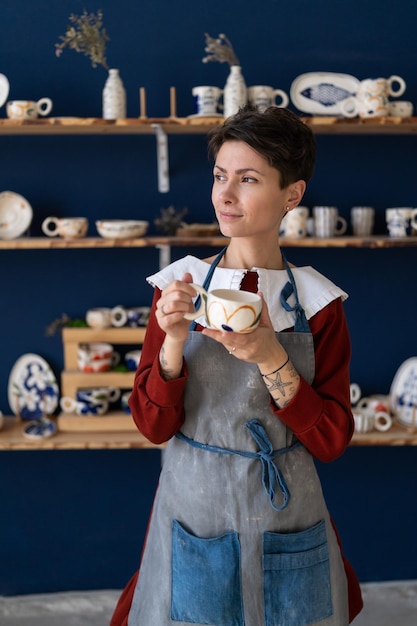 Successful handmade pottery workshop owner refreshing with drink between master classes