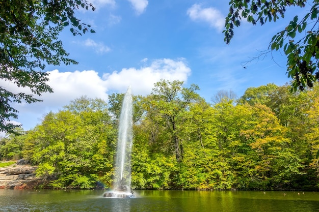 Sunny summer day in the Ukrainian park in the city of Uman Fountain in the center of a small pond