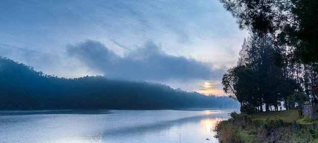 Sunrise near hill and lake with trees