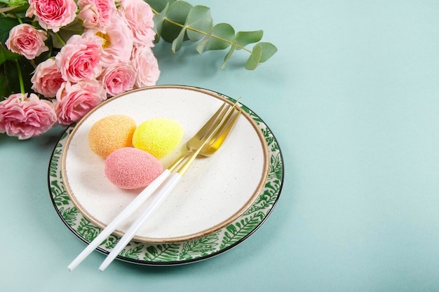 Table setting for celebrating easter plates cutlery colored eggs and spring pink flowers on the