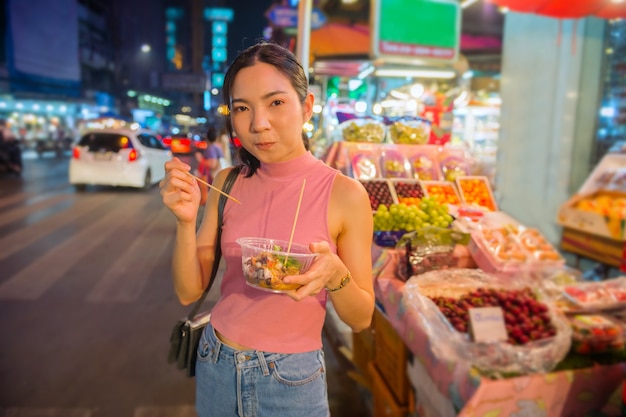 Photo thai-chinese tourists stroll around and sample street food at yaowarat road, chinatown, bangkok