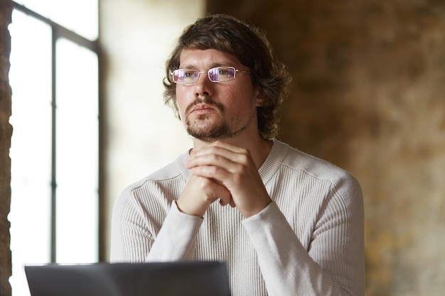 Thoughtful young man freelancer working on laptop at home.