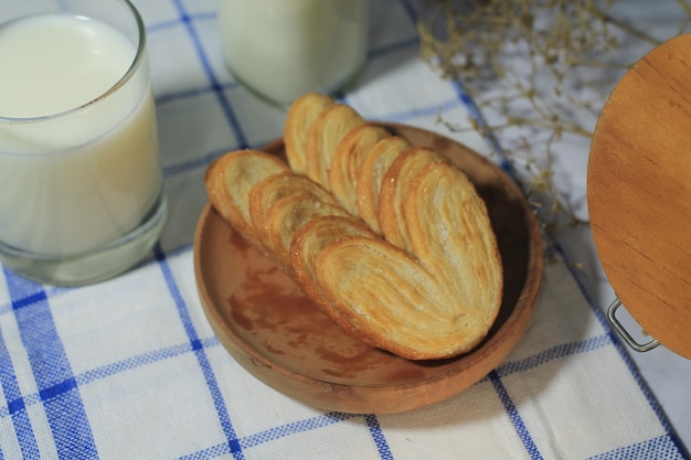 Top view delicious pastry on a wood plate with glass of milk