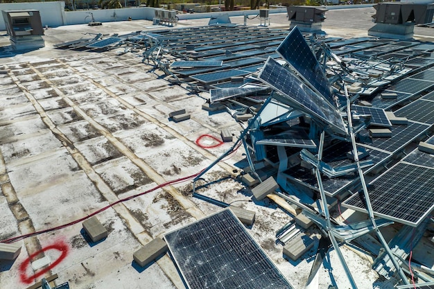 Top view of destroyed by hurricane Ian photovoltaic solar panels mounted on industrial building roof for producing green ecological electricity Consequences of natural disaster in Florida