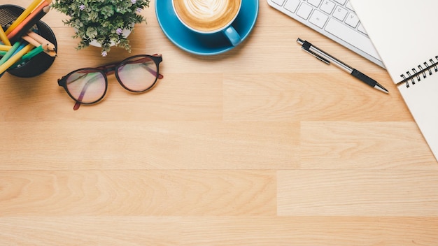 Photo top view wooden office desk with keyboard computer cup of coffee pen eyeglass and notebook copy space mock upx9