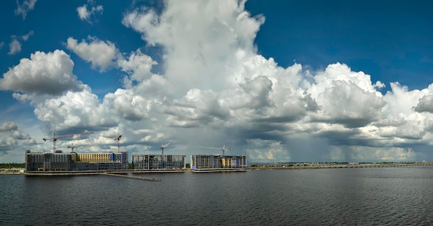 Tower cranes and frame structure of high residential apartment buildings at construction site on sea bay shore Real estate development at waterfront