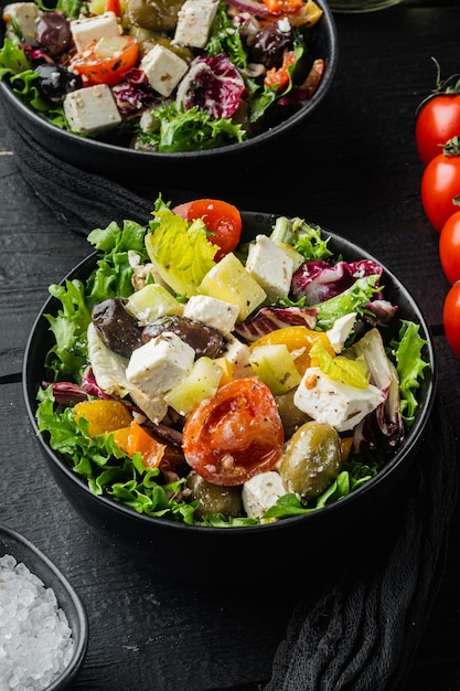 Traditionele Griekse salade met verse groenten, feta en olijven, op zwarte houten tafel