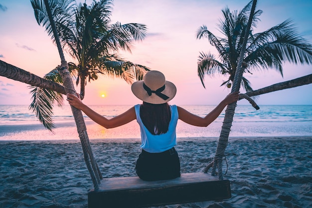 Photo traveler woman travel and relax on swing in sunset beach thailand