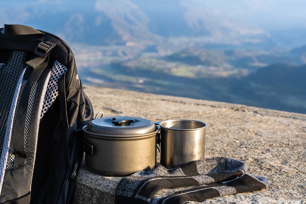 Trecking or hiking equipment set. Bagpack, socks, metal cup, and kettle pot. Outdoor activity concept.