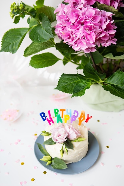 Very beautiful bento cake decorated with fresh eustoma flowers on the background of sweets and the inscription happy birthday balloons flowers Holiday concept