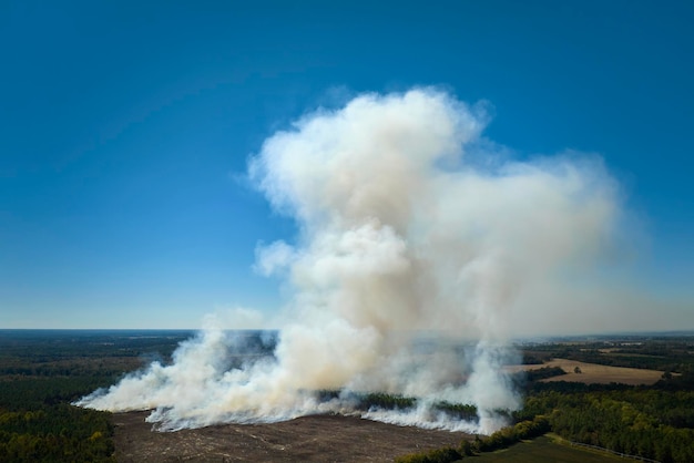 View from above of dense smoke from woodland and field on fire rising up polluting air Concept of natural disaster