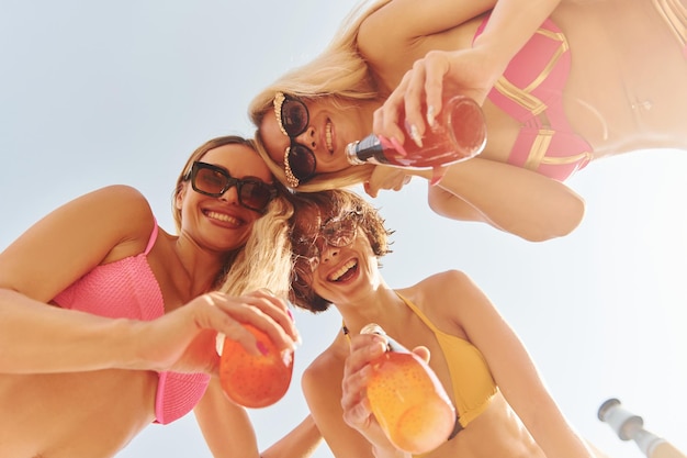 View from below Women in swimsuits have fun outdoors together at summertime