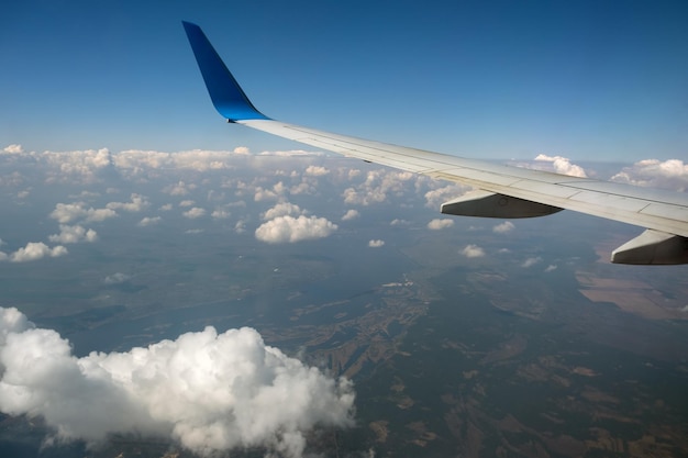 Foto vista dell'ala dell'aereo a reazione dall'interno che sorvola le nuvole gonfie bianche nel cielo blu. concetto di viaggio e trasporto aereo.