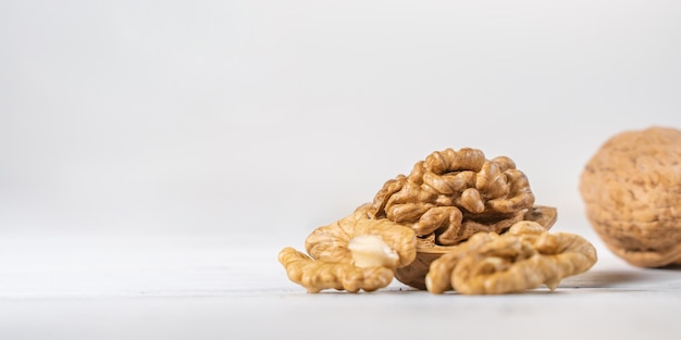 Walnuts kernels on white wooden desk with place for text. Pile of whole walnut shells