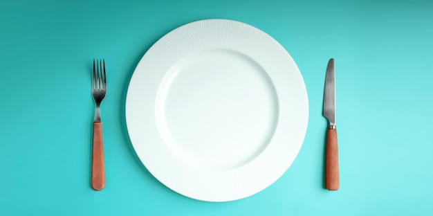 White Empty Plate with Fork and Knife Lay on Blue Table Background Food Shortage World Food Crisis Issue Table Top View