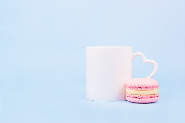 Photo white mug and pink macaron on light blue background