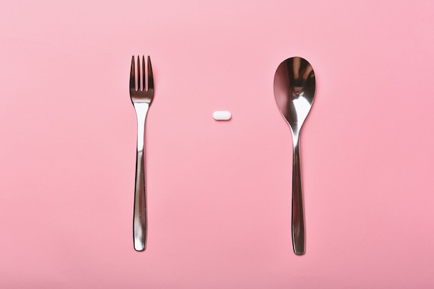 White pill with spoon and knife